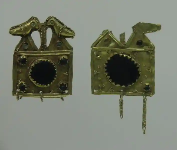 A gold ornament designed with two birds and solar symbol